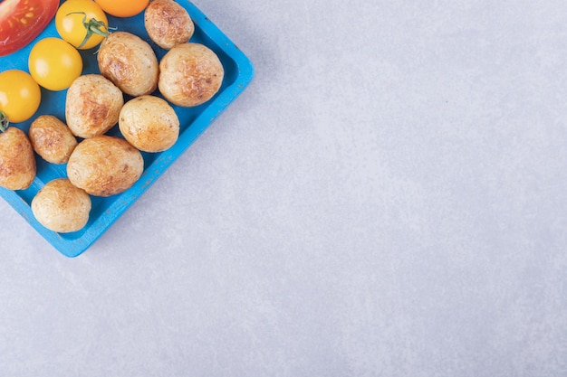 Gebakken aardappelen en tomaten op blauw bord.