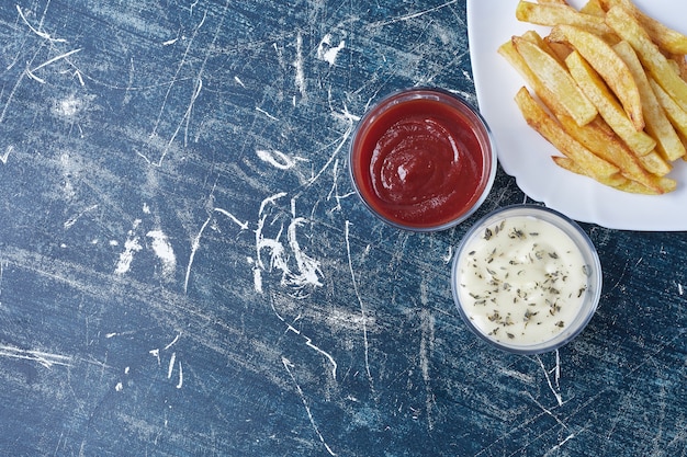 Gratis foto gebakken aardappelen met ketchup en mayonaise.