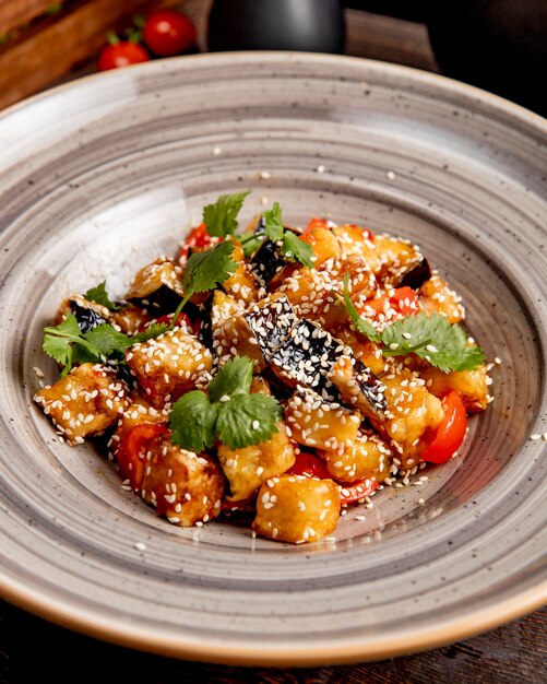 Gebakken aubergines met tomaten bereid in saus en geserveerd met koriander