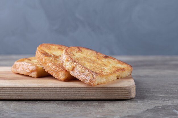 Gebakken brood met ei op een houten bord.