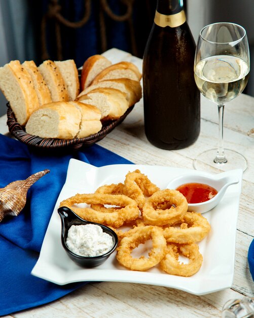 Gebakken calamares geserveerd met mayonaise en zoete chilisaus, witte wijn en brood