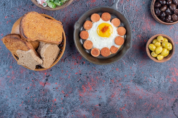 Gebakken ei geserveerd met gegrilde worst en kruiden op een houten schotel.