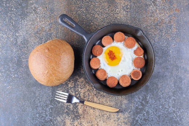 Gebakken ei met worstjes in een pan met broodje