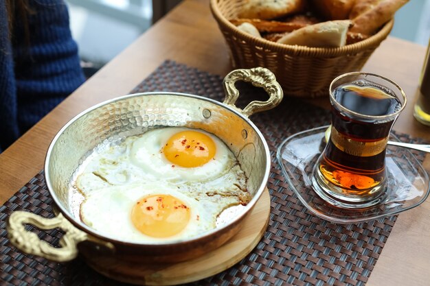 Gebakken eieren in de pan op de houten plank thee in armudy brood