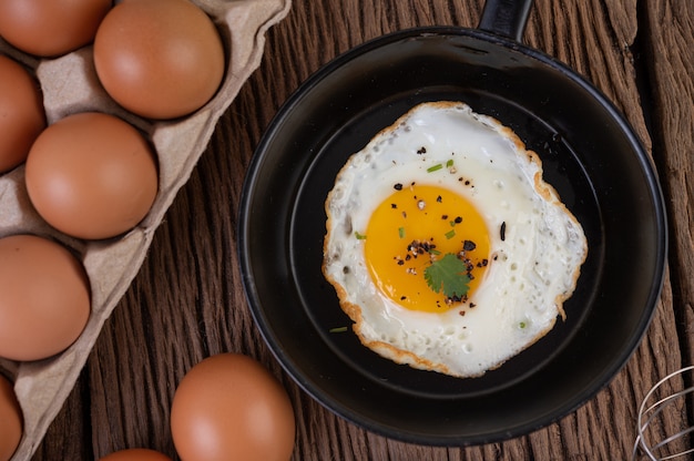 Gratis foto gebakken eieren in een koekenpan en rauwe eieren, biologisch voedsel voor een goede gezondheid, rijk aan eiwitten