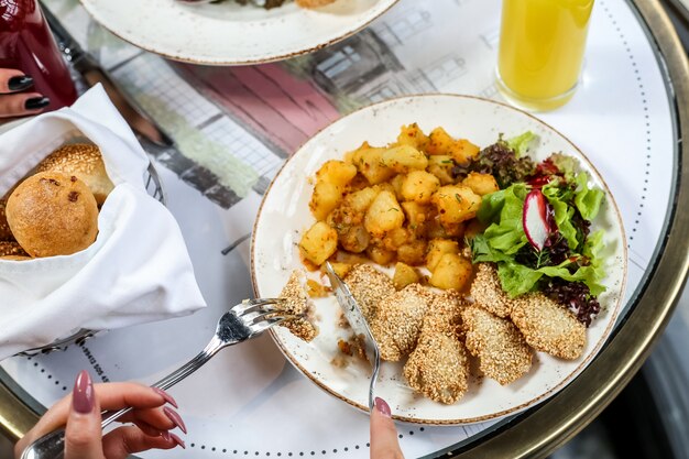 Gebakken kip met aardappel, radijs, sla en broodjes