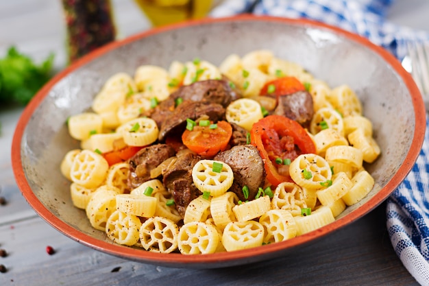 Gebakken kippenlever met tomaat en garnering van pasta