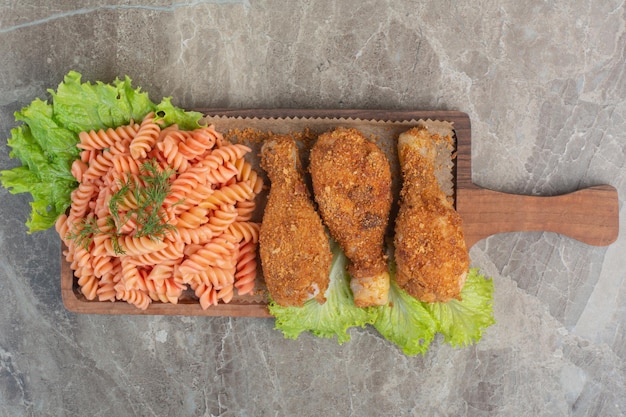 Gebakken krokante kipnuggets met heerlijke macaroni op een houten bord.