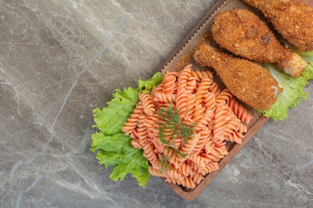 Gebakken krokante kipnuggets met heerlijke macaroni op houten bord.