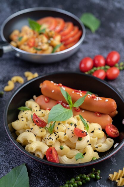 Gebakken macaroni en worst in een koekenpan.