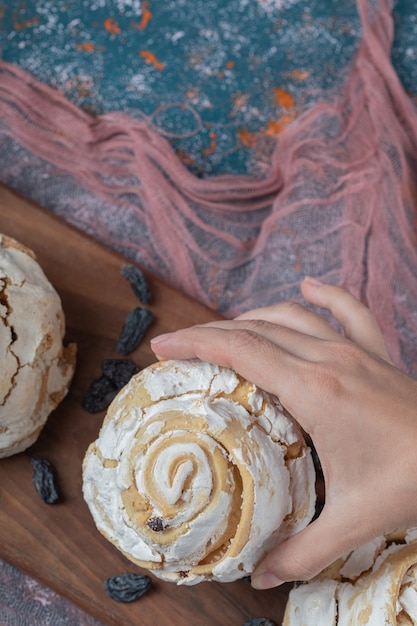 Gebakken meringue cookie met zwarte rozijnen op een houten bord.