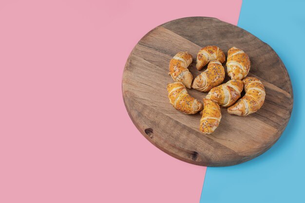 Gebakken mini croissant cookies op een houten bord.