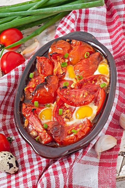 Gratis foto gebakken tomaten met knoflook en eieren versierd met groene uien