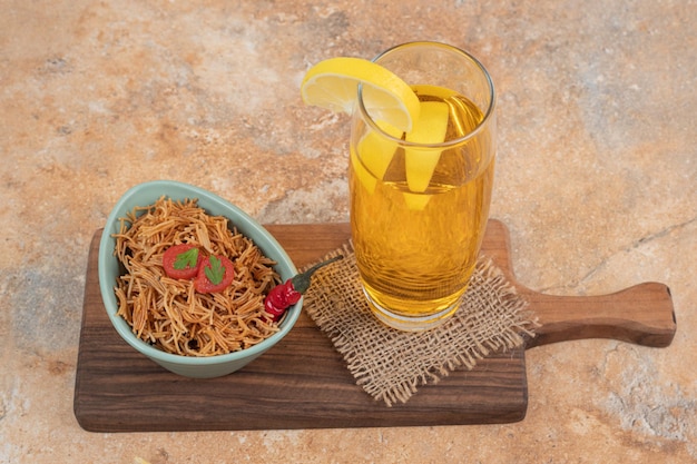 Gebakken vermicelli met tomaat en glas sap op een houten bord.