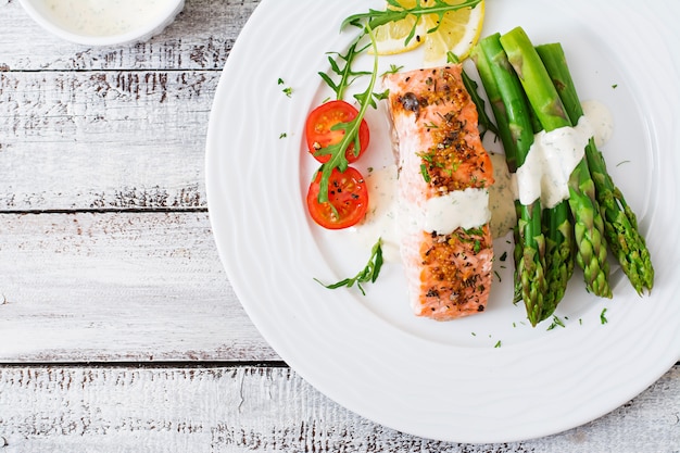 Gebakken zalm gegarneerd met asperges en tomaten met kruiden. Bovenaanzicht