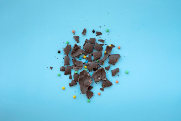Gebarsten chocolade met kleine snoepjes op blauwe tafel