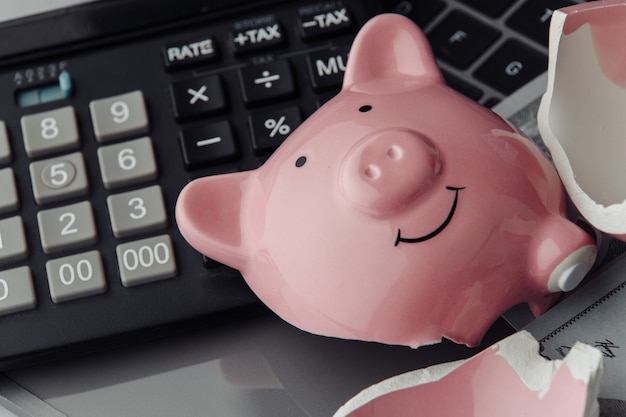 Gebroken roze spaarvarken op een toetsenbord en een rekenmachine. financiën en faillissementsidee