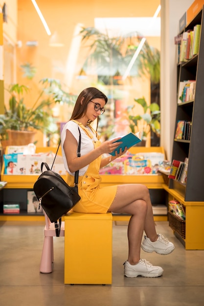 Gratis foto geconcentreerd de lezingsboek van het tienerschoolmeisje op zetel