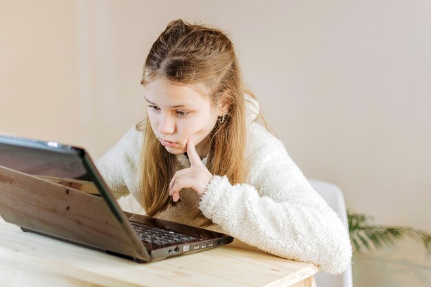 Geconcentreerd meisje die laptop thuis met behulp van