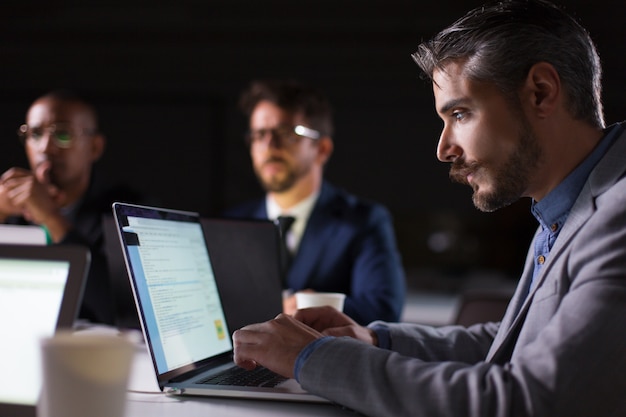 Geconcentreerde bebaarde kantoormedewerker kijken naar laptop