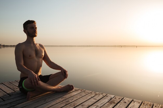 Geconcentreerde jonge sportman maakt yoga-meditatie-oefeningen