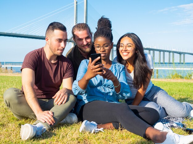 Geconcentreerde jonge vrienden die smartphone gebruiken openlucht