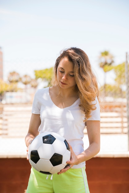 Gratis foto geconcentreerde jonge vrouw met voetbalbal