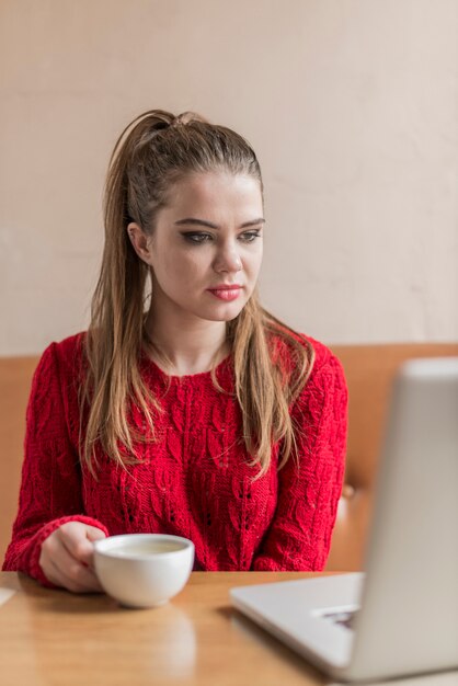 Geconcentreerde jonge vrouw op zoek naar haar laptop