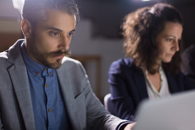 Geconcentreerde knappe zakenman die laptop bekijkt