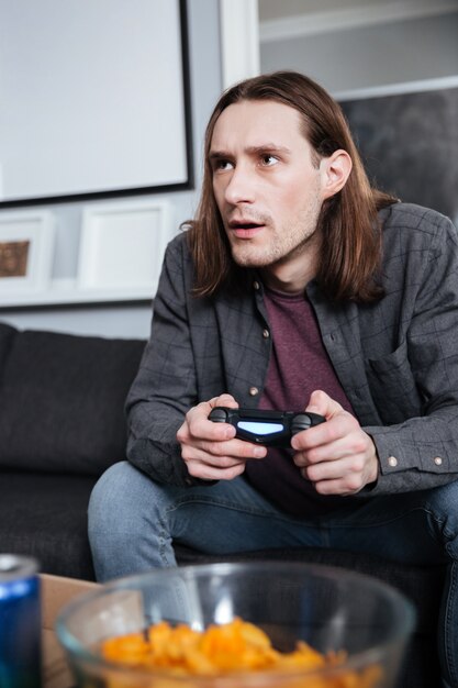 Geconcentreerde man gamer om thuis te zitten binnenshuis