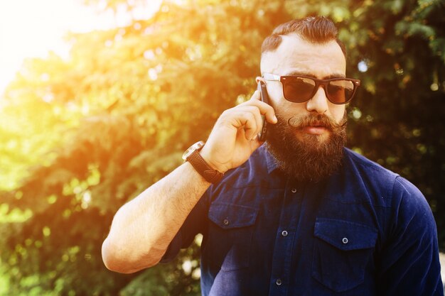 Geconcentreerde man praten over de telefoon bij zonsondergang