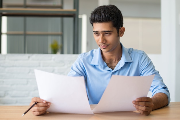 Geconcentreerde mannelijke manager die aandachtig document bekijkt