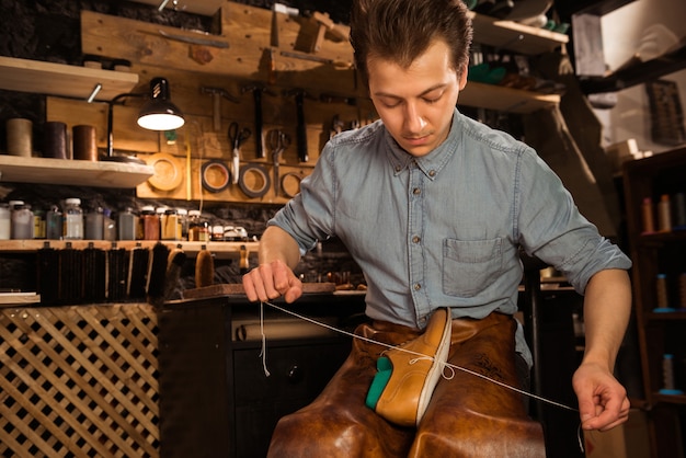 Geconcentreerde schoenmaker in werkplaats die schoenen maakt