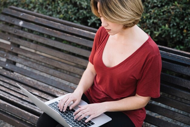 Gratis foto geconcentreerde vrouw die laptop in park met behulp van