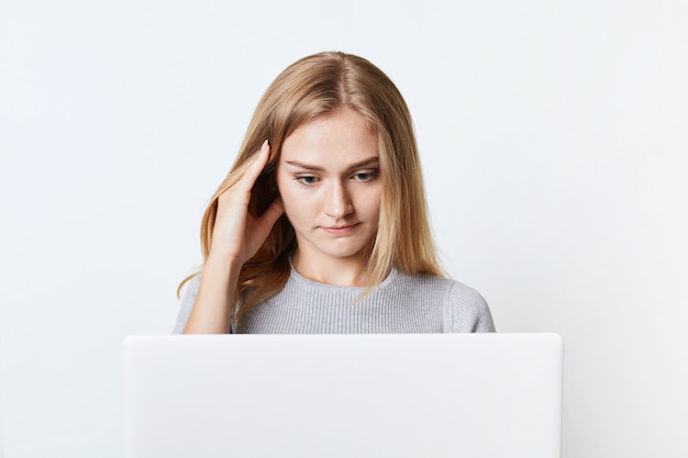 Geconcentreerde vrouwelijke freelancer werkt op laptopcomputer.