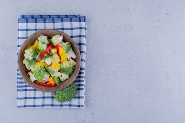 Gedeelte van broccoli en pepersalade in een kom op gevouwen handdoek op marmeren achtergrond. Hoge kwaliteit foto