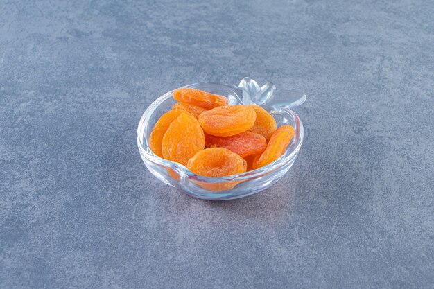 Gedroogde abrikoos in een glazen kom op het marmeren oppervlak