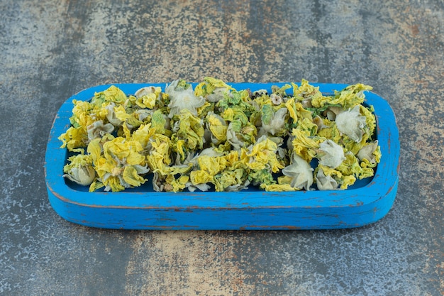 Gedroogde chrysantenbloemblaadjes op blauw bord.