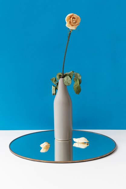 Gedroogde witte roos in een vaas op een glanzend rond dienblad
