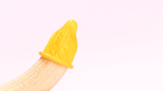 Geel ongepakt condoom op een banaan.