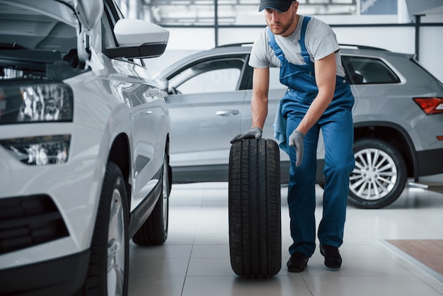 Geen probleem. Monteur met een band bij de reparatiegarage. Vervanging van winter- en zomerbanden