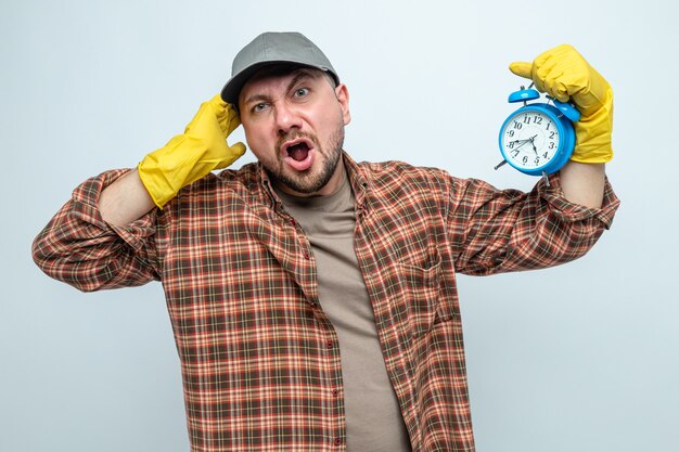 Geërgerd Slavische schonere man met rubberen handschoenen met wekker