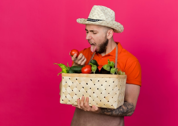 Gratis foto geërgerde mannelijke tuinman met tuinhoed steekt tong uit