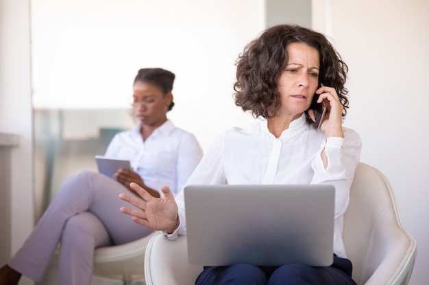 Geërgerde onderneemster die aan partner op telefoon spreekt