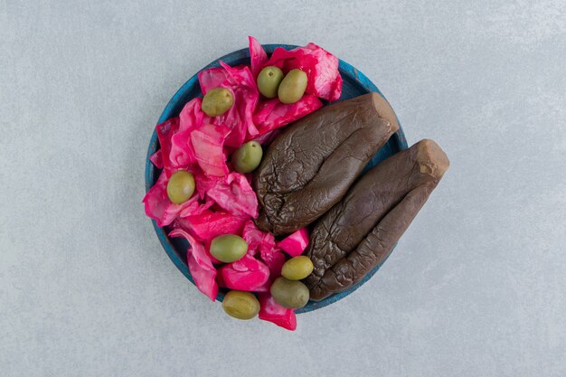 Gefermenteerde aubergines en kool op blauw bord.