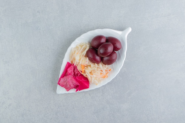 Gefermenteerde kool en fruit op bladvormige plaat.