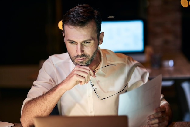 Gefocuste man die laat aan het werk is in zijn thuiskantoor