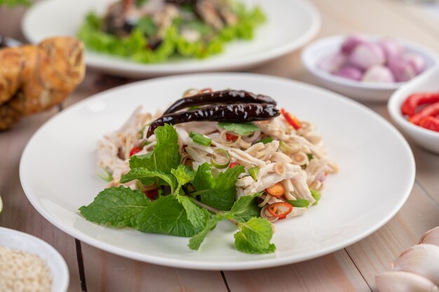 Gefrituurde makreel gegarneerd met laos, peper, munt, rode ui in een witte schotel.