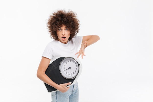 Gefrustreerde jonge casual vrouw wijzend op gewichten