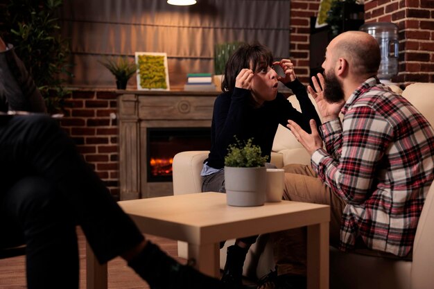 Gefrustreerde mensen die vechten tijdens een paartherapiesessie met een specialist, die ruzie hebben over huwelijksproblemen. Relatieproblemen proberen op te lossen met professioneel advies van een therapeut.